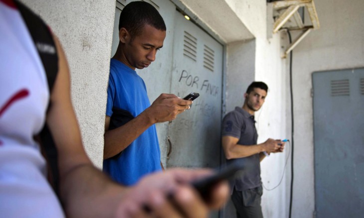 Jóvenes cubanos viendo sus celulares