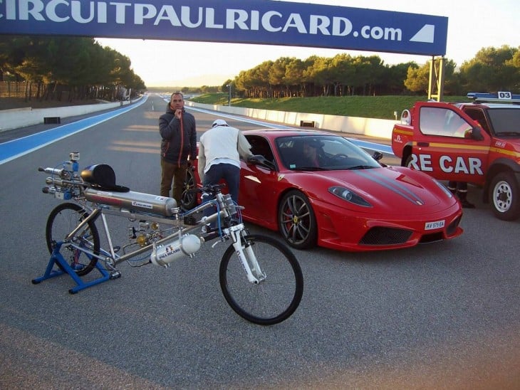 bicicleta con cohetes junto a ferrari