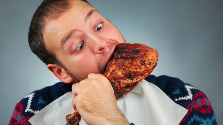 Hombre comiendo una pierna de pollo