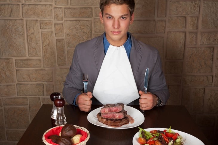 Hombre sentado comiendo un bistec