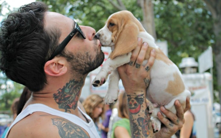 hombre con tatuajes besando a un cachorro
