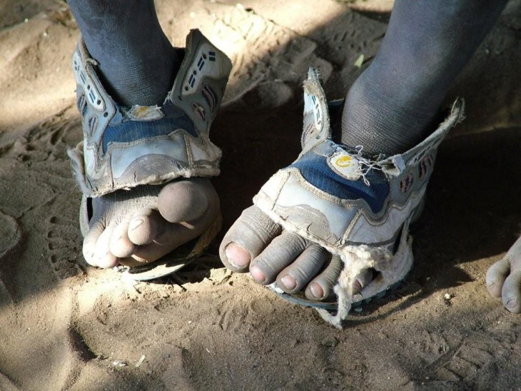 niño pobre con zapatos rotos