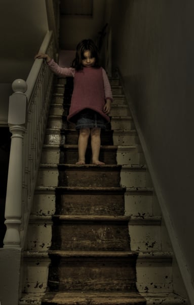 niña bajando las escaleras oscuras