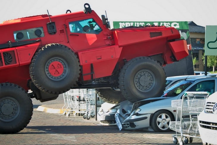 marauder rojo aplastando a dos autos en un estacionamiento