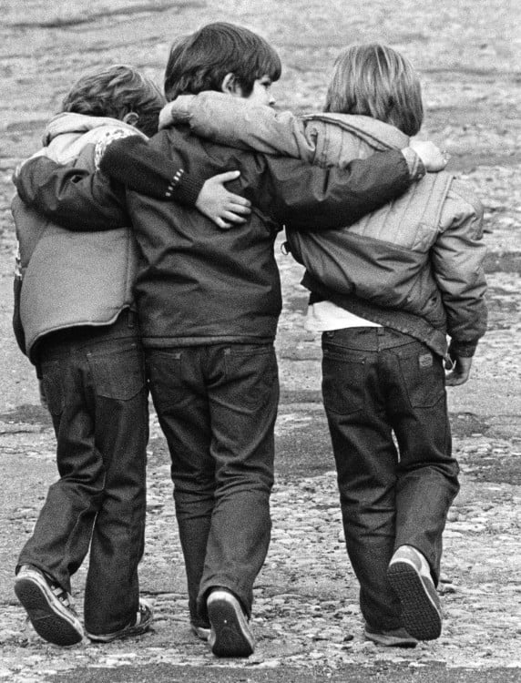 Niños abrazados van caminando