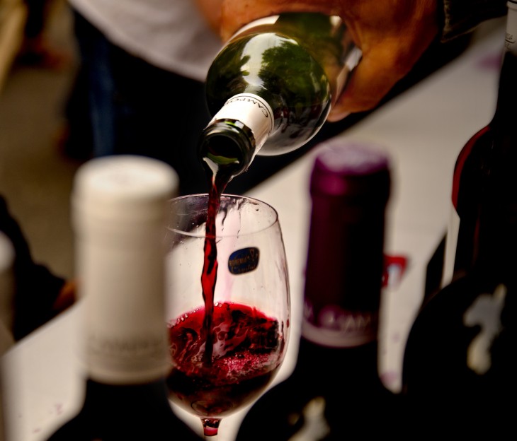 botella de vino tinto virtiendose sobre una copa de cristal 