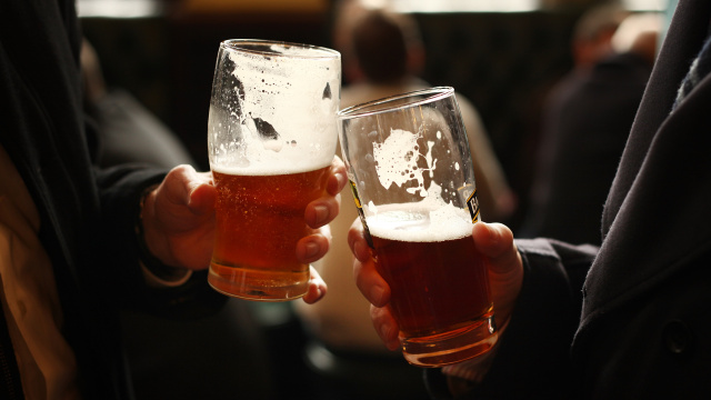 manos de dos personas con una cerveza brindando 