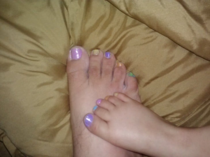 pie de un hombre con las uñas pintadas del mismo color que las del pie de su hija 