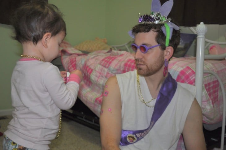 Bebé adornando a su papá con coronas y collares 