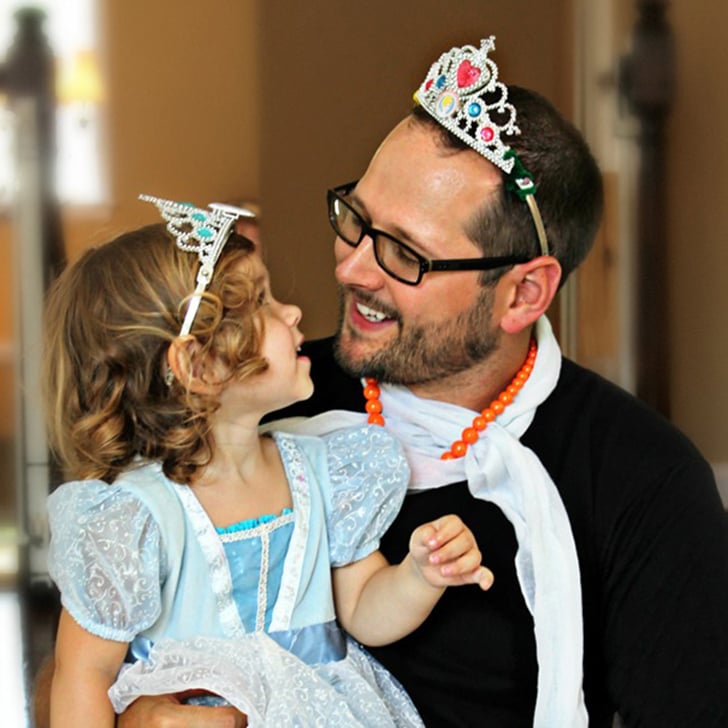 hombre con una corona en su cabeza cargando a su hija vestida de princesa 