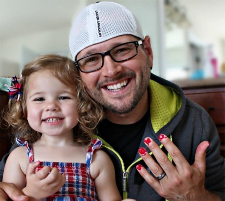 Hombre junto a su niña mostrando sus uñas pintadas en color rojo 