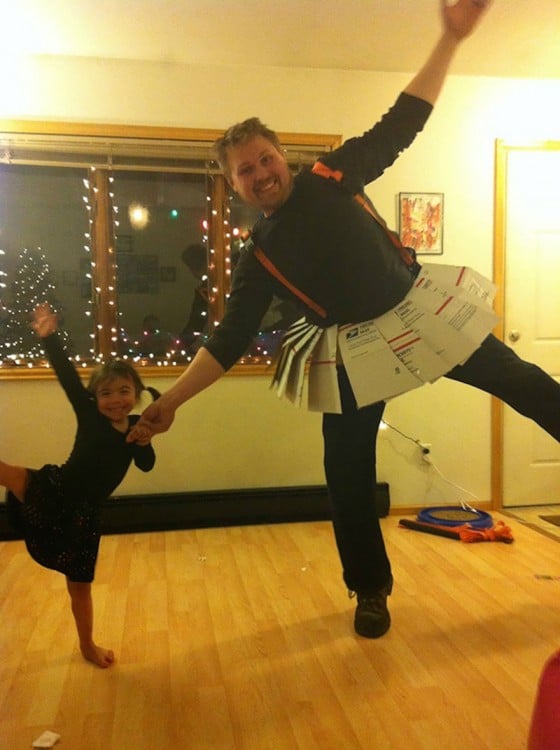 Hombre con una falda hecha de papel bailando a lado de su hija 