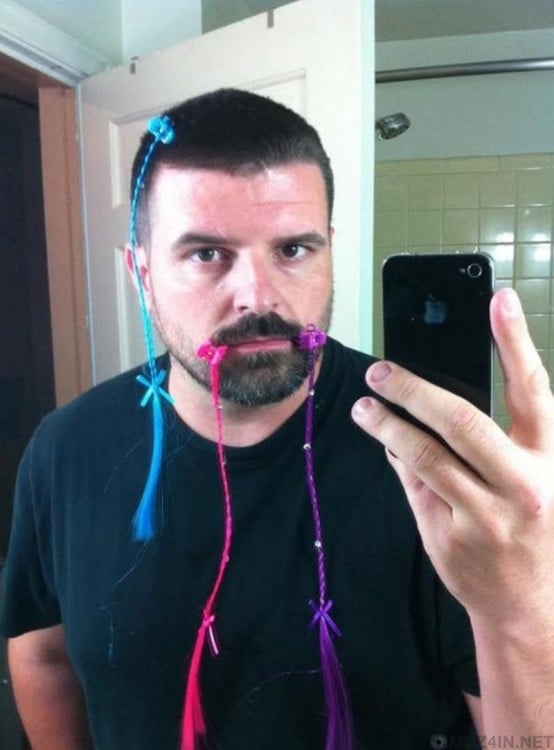 selfi de un hombre frente al espejo con trenzas adornando su barba 