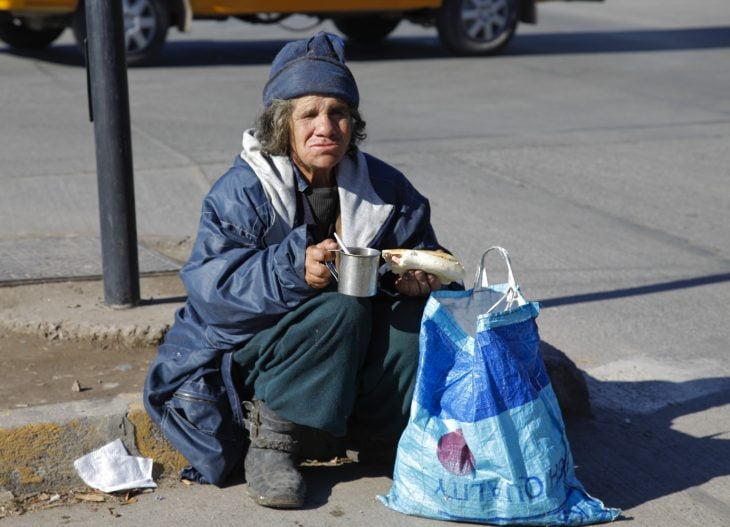 Indigente comiendo en la calle