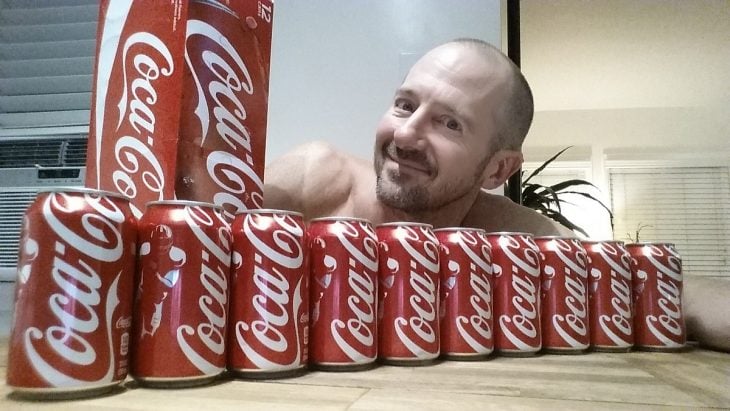 Hombre entre latas de Coca Cola