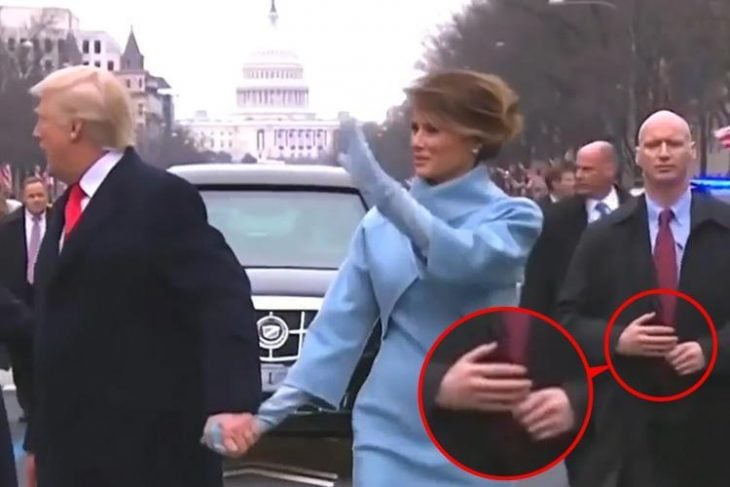 Trump, esposa y guradia con brazos falsos y rueda señalando