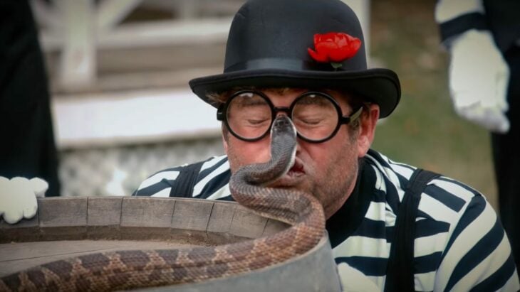 Serpiente muerde a un hombre con lentes y sombrero en el en el rostro