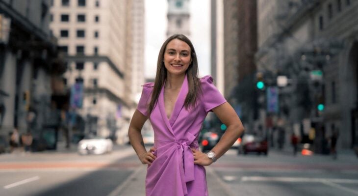 la demócrata Alexandra Hunt sonriendo a mitad de la calle en un vestido rosa