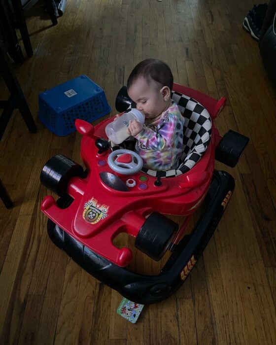 Sobrevivientes bebé bebiendo biberón en su carro de juguete
