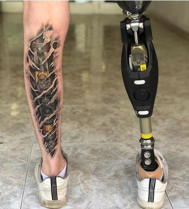 Tatuaje que imita la prótesis de la pierna derecha por medio de la imitación del mecanismo de la misma tatuaje en la pierna Simetría biónica