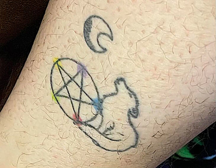Tatuaje de un lobo sobre un pentagrama aullándole a la luna