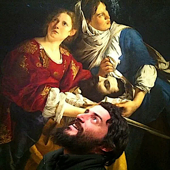 Un visitante del museo moderno Holofernes sonriente posa junto a Judith y su doncella