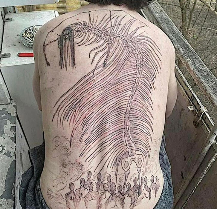 Tatuaje que muestra a un monstruo con costillas abiertas y que es seguido por un grupo de sombras en un paisaje apocalítico