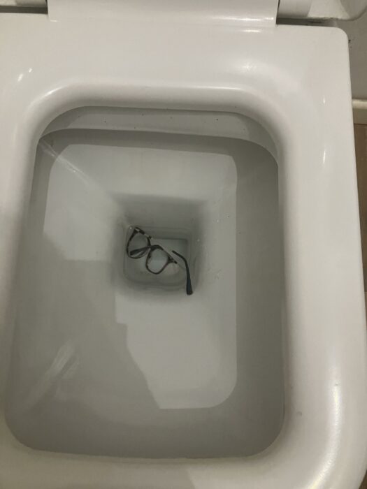 Lentes en el fondo del inodoro aparentemente cayeron ahí retrete taza de baño