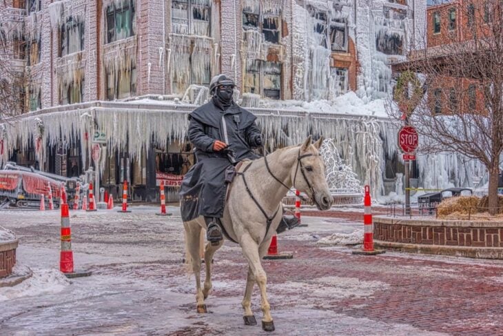 Paisaje urbano invernal en Omaha policía cabalgando por la calle y los edificios cubiertos de carámbanos