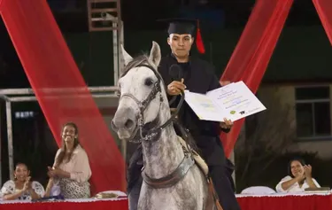 chico sobre caballo recibiendo título graduación