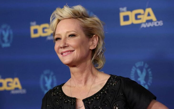 Anne Heche sonriendo ante las cámaras con vestido negro