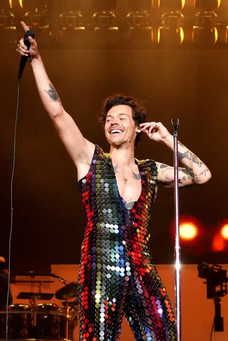 Harry STyles en el escenario señalando y con ropa de lentejuelas