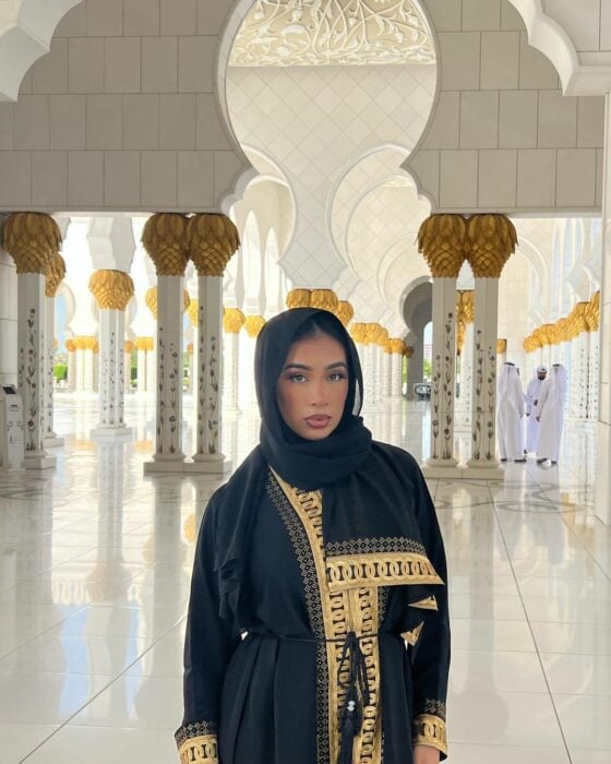 Jenny Martínez vistiendo indumentaria tradicional negra con bordado dorado y con la cabeza cubierta, dentro de una mezquita