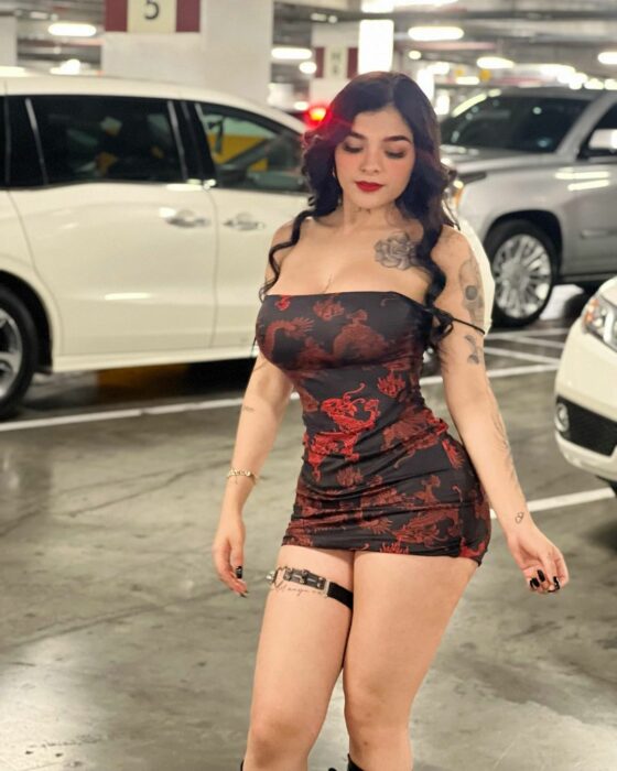 Kareli RUiz en un estacionamiento vestido estampado rojo negro