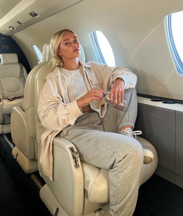 Katie Sigmond influencer en un avión con pants casuales grises