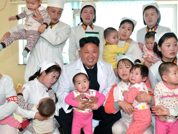 El líder norcoreano Kim Jong-un toma a un bebé y es acompañado por personal que sostiene a varios infantes vestidos con rosa