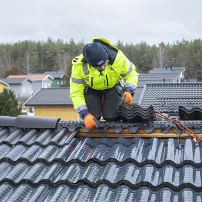 Tejas de energía solar y un hombre instalándolas