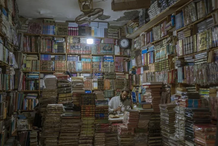 Tendero de librería reparando un libro dañado a la luz de la lámpara