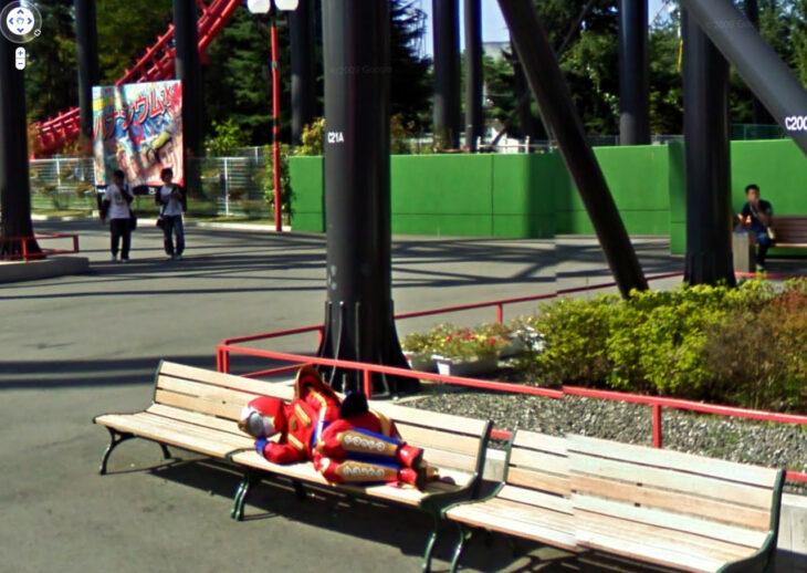 SUper sentai foto de google maps disfraz cosplay recostado en una banca pública descansando