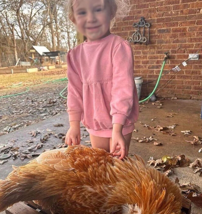 Niña posando con gallo muerto