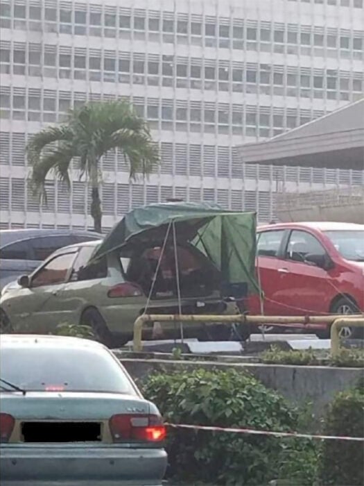 Padre acampando en el estacionamiento de un hospital