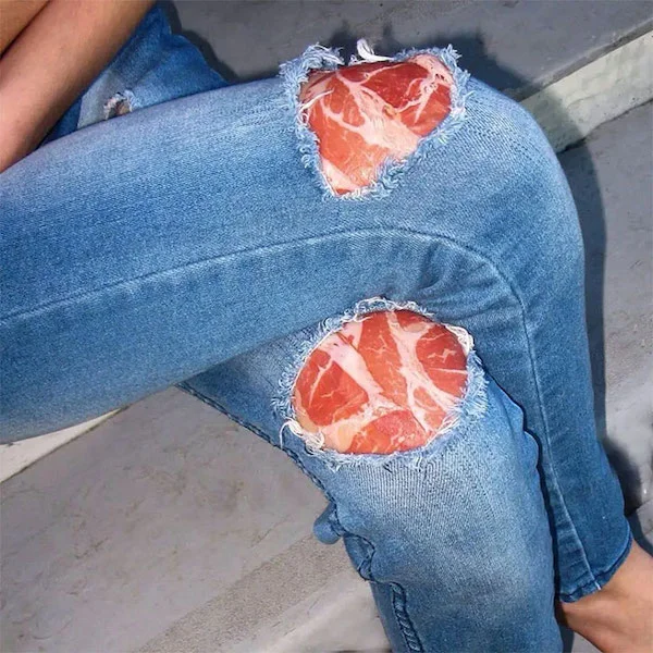 pantalones de mexclilla con agujeros dejando que se vean bistecs carne por debajo