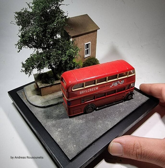 Autobús Inglés rojo de dos pisos pasando por un paraje de reino unido frente a casa diorama