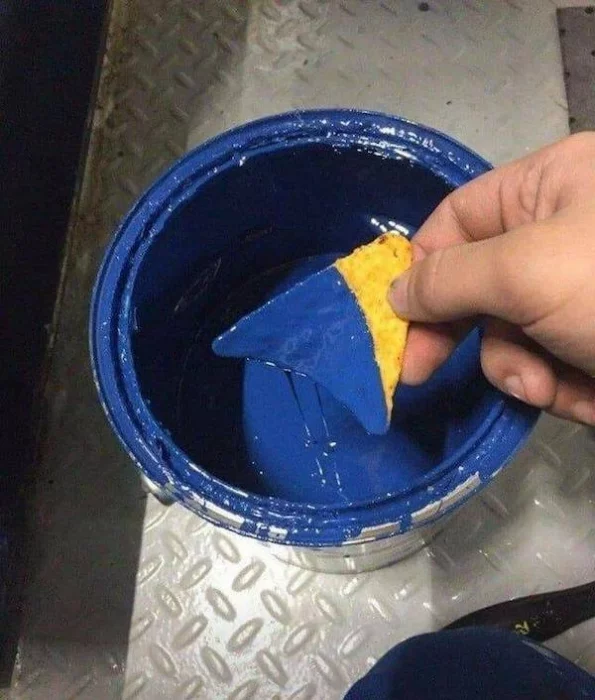 Hombre sumergiendo un nacho en pintura azul