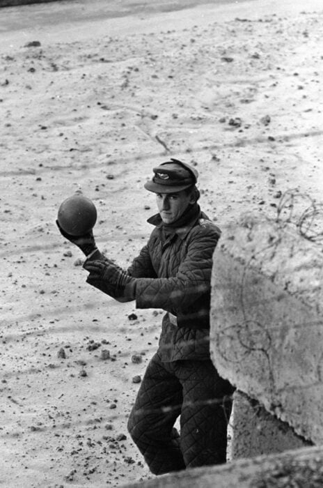 Hay bolita soldado regresando el balón a un niño que juega al oeste del muro de berlín