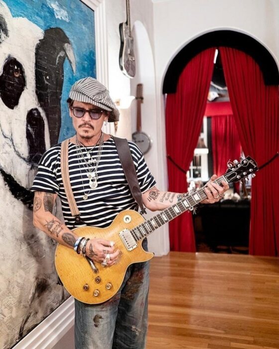 Johnny depp con camisa a rayas y guitarra eléctrica