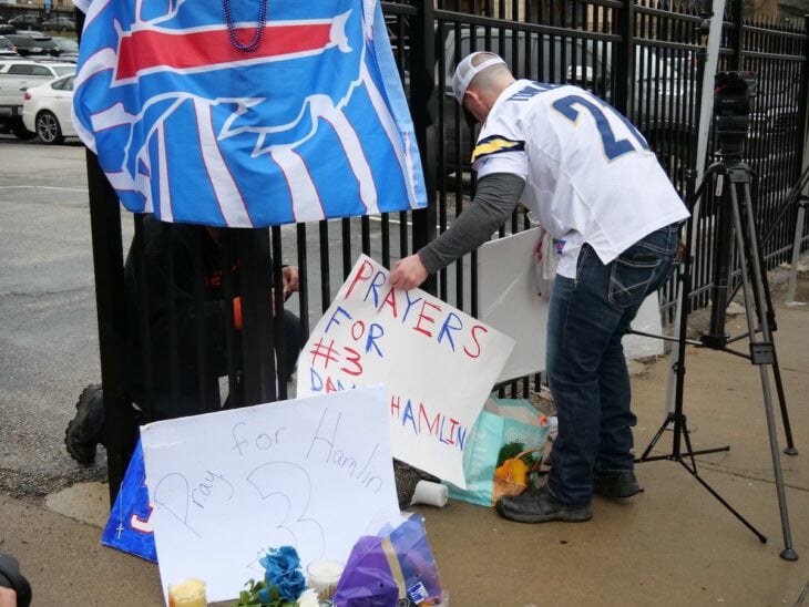 Hombre con pancarta que ofrece oraciones para Damar Hamlin a las afueras del hospita de la universidad de cincinnati