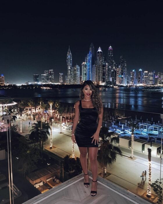Shie Lee en la terraza vestido negro frente a la ciudad vista panorámica