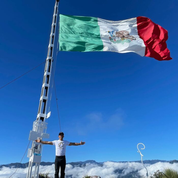 Fernando Villatoro Garza posando junto a la bandera nacional celebrando su 365 ascenso al cerro de la silla Monterrey
