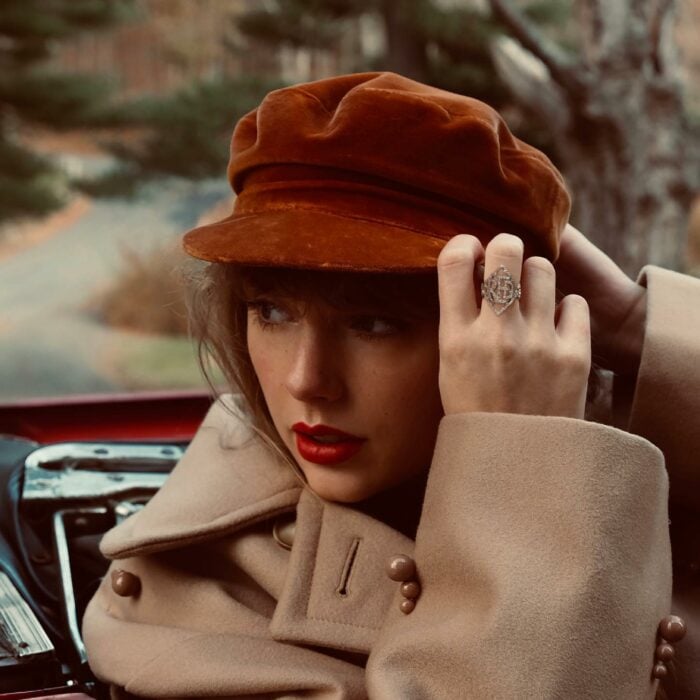 Taylor Swift con gorra roja y saco beige labial rojo